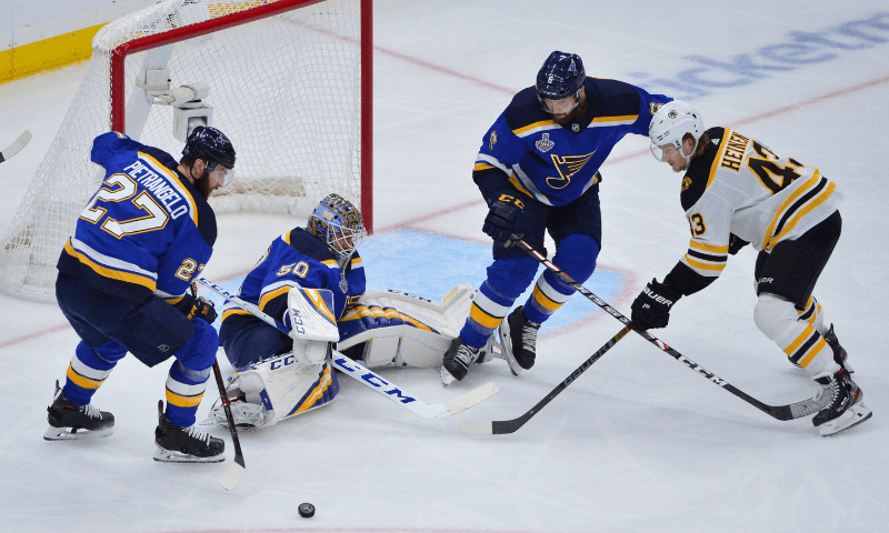 St. Louis Blues and Boston Bruins players battle for the puck